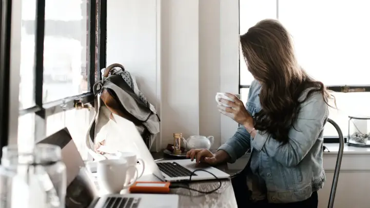 パソコン作業をしながらコーヒーを飲む女性